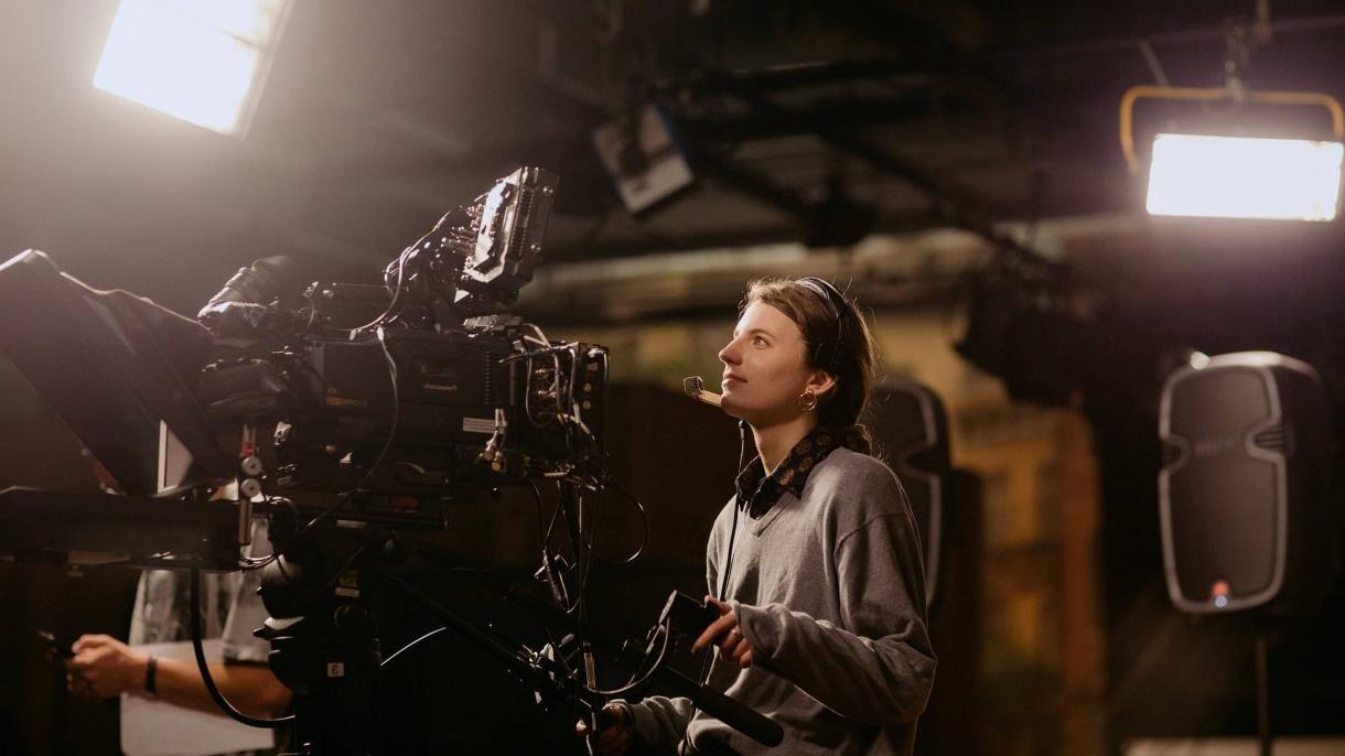 Asbury University Undergraduate Student behind a camera filming in a studio