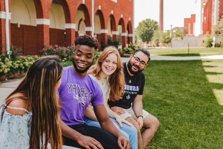 Four Asbury University students sit on campus engaged in conversation