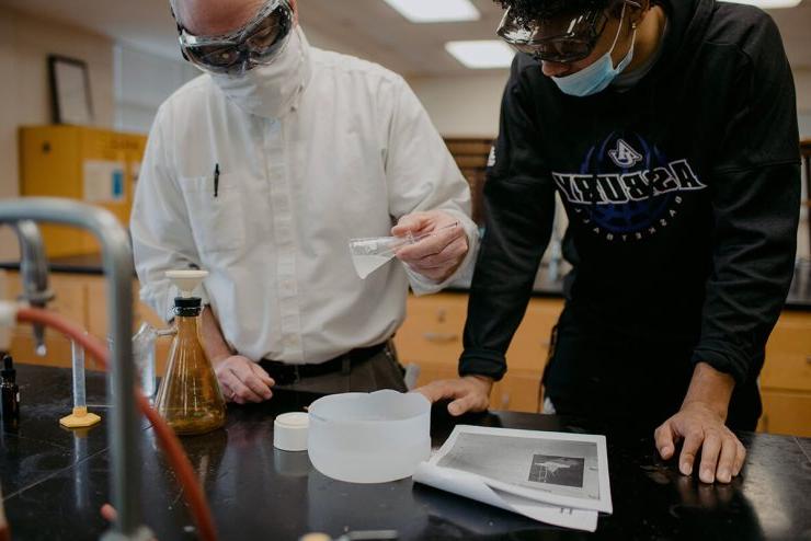 Chemistry teacher instructs Asbury University student in a school sweatshirt in classroom laboratory